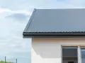 Nowoczesny dach z blachy, solidna obróbka blacharska i biała elewacja domu.