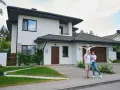 Szczęśliwa rodzina przed nowoczesnym domem. Szacowany koszt budowy domu 220m2.