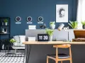 Biuro z zegarami pokazującymi czas w Nowym Jorku, Londynie i Tokio na ścianie w kolorze navy. Na biurku laptop, lampa i gramofon.