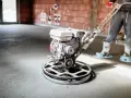 Pracownik wygładza posadzkę mechanicznie. Sprawdź, jaka jest styrobeton cena za m2 dla Twojego projektu.