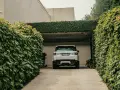 Biały Range Rover wjeżdża na podjazd otoczony bujną zielenią. Naturalna ściana z bluszczu to świetna alternatywa co zamiast kostki na podjazd.