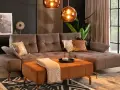 Sofa w kolorze taupe, czyli eleganckim połączeniu brązu i szarości, z pomarańczową pufą i miedzianymi dodatkami.
