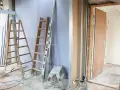 Remont mieszkania 60m2 w toku. Drabiny, poziomica i materiały budowlane wskazują na prace.