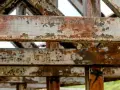 Widoczne są zardzewiałe, metalowe belki konstrukcyjne. To przykład tego, co to jest korozja – proces niszczenia metalu pod wpływem czynników atmosferycznych.