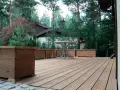 Drewniany taras wentylowany z donicami i stolikiem. Sprawdź atrakcyjną cenę za m2!