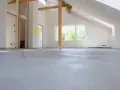 Nowe wnętrze z drewnianymi belkami i oknem, gotowe na posadzkę maszynową. Zastanawiasz się, ile za metr posadzki maszynowej?