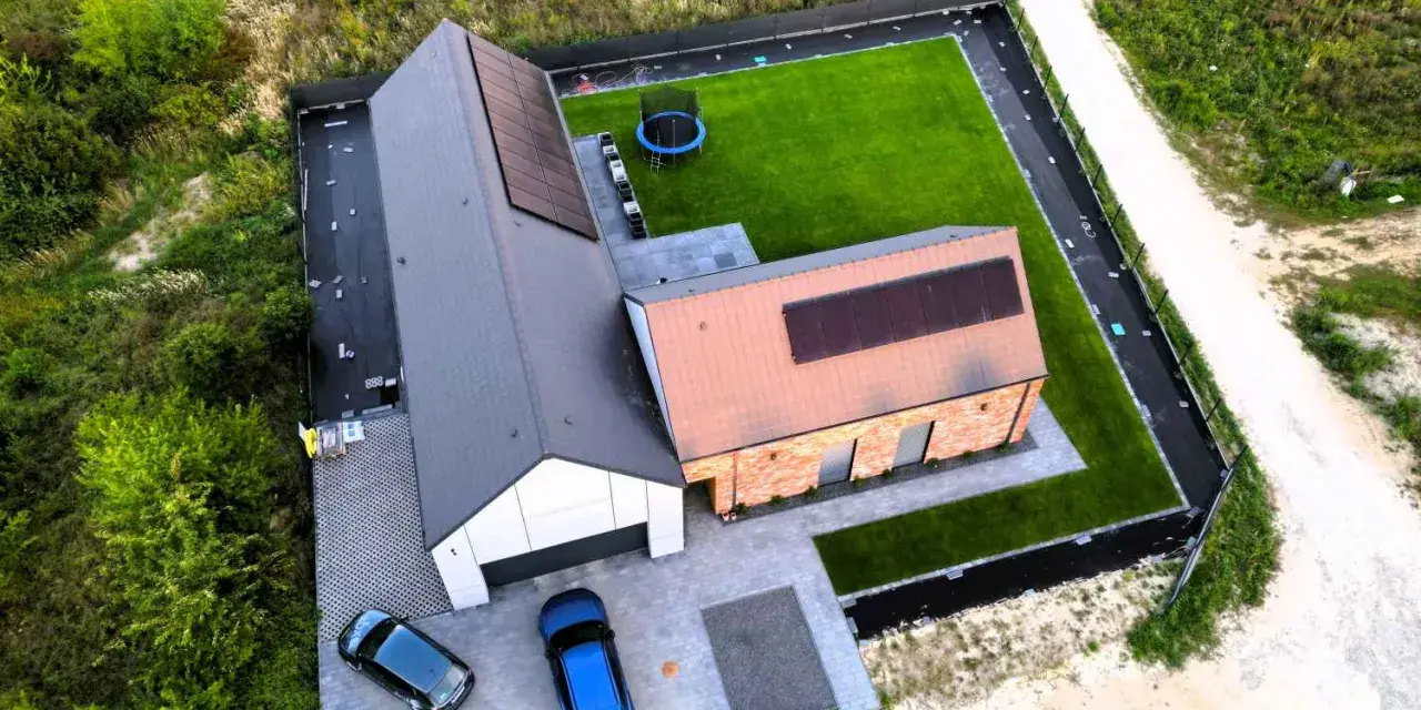 Nowy dom z panelami słonecznymi i zadbanym ogrodem. Zastanawiasz się, ile realnie kosztuje budowa domu?