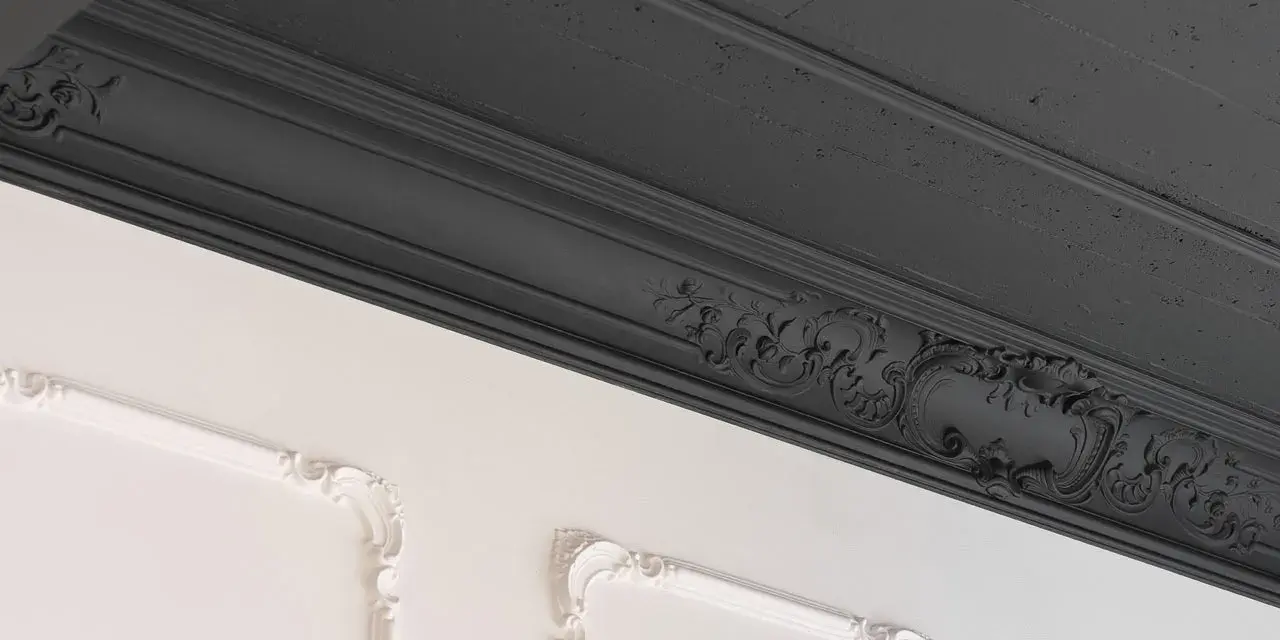 Elegancka sztukateria, ciemnoszary sufit i białe panele ścienne z ozdobną rozetą tworzą wyrafinowaną kompozycję.