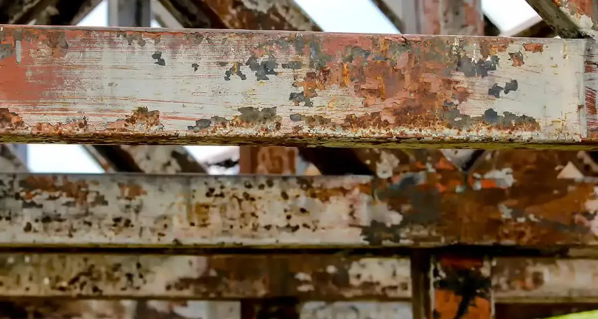 Widoczne są zardzewiałe, metalowe belki konstrukcyjne. To przykład tego, co to jest korozja – proces niszczenia metalu pod wpływem czynników atmosferycznych.