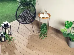 Nowoczesne deski kompozytowe to świetny pomysł, czym wyłożyć balkon. Wygodne krzesło, stolik i latarenki tworzą przytulną atmosferę.