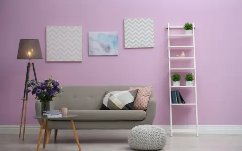 Przytulny salon z szarą kanapą, stolikiem kawowym, lampą i dekoracjami na ścianie w odcieniu **kolor liliowy**.