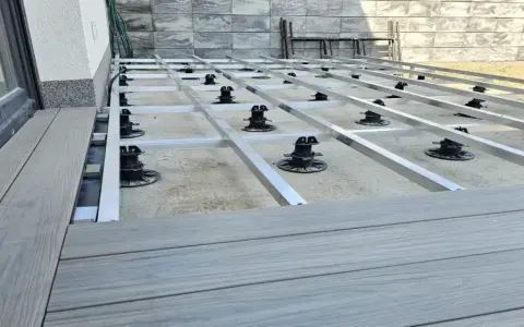Montaż tarasów z deski kompozytowej. Widoczna konstrukcja nośna z aluminiowych profili i regulowanych podpór.