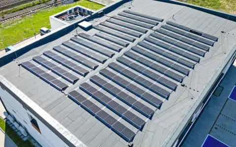 Duży dach płaski pokryty panelami fotowoltaicznymi, które zbierają energię słoneczną.