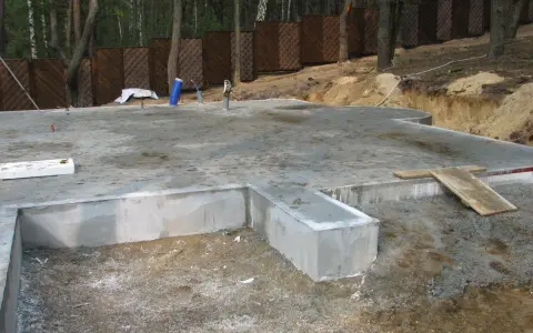 Fundament płytowy w trakcie budowy, z widocznymi elementami betonowymi i zbrojeniem.