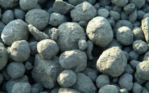 Zbliżenie na stos szarych, nieregularnych grudek cementu.