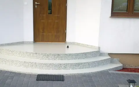 Schody i balkon z żywicy przed drzwiami wejściowymi do domu.