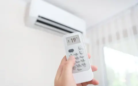 Dłoń trzymająca pilot do klimatyzacji, ustawiona na 19°C. Zastanawiasz się, ile kosztuje montaż klimatyzacji?