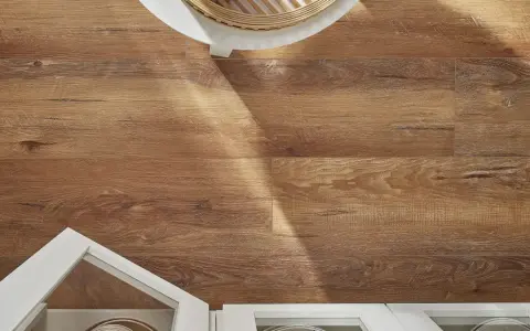 Drewnopodobne panele laminowane czy winylowe tworzą ciepłą podłogę. Białe meble i pleciony kosz dodają stylu.