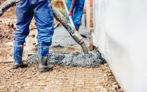 Pracownicy wylewają beton na zbrojenie. Sprawdź aktualną suchy beton cena 1m3.