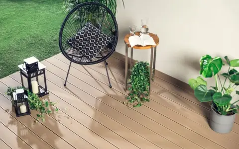 Nowoczesne deski kompozytowe to świetny pomysł, czym wyłożyć balkon. Wygodne krzesło, stolik i latarenki tworzą przytulną atmosferę.