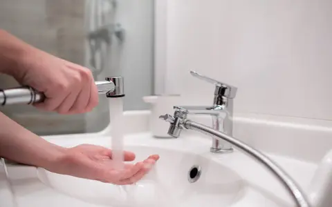 Dłoń pod strumieniem wody z podręcznego bidetu. To proste rozwiązanie do higieny osobistej.