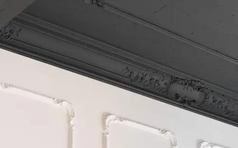 Elegancka sztukateria, ciemnoszary sufit i białe panele ścienne z ozdobną rozetą tworzą wyrafinowaną kompozycję.