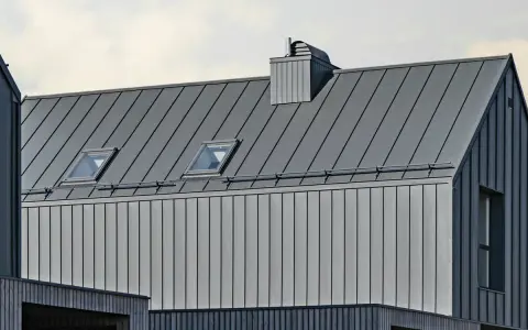 Nowoczesny dach z blachy na rąbek, z oknami połaciowymi i kominem. Sprawdź blacha na rąbek cena m2.