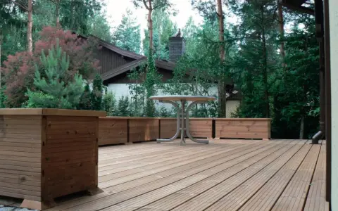 Drewniany taras wentylowany z donicami i stolikiem. Sprawdź atrakcyjną cenę za m2!