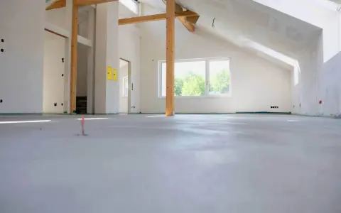 Nowe wnętrze z drewnianymi belkami i oknem, gotowe na posadzkę maszynową. Zastanawiasz się, ile za metr posadzki maszynowej?