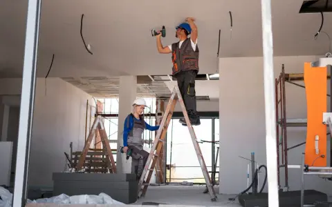 Dwóch budowlańców na drabinach montuje instalację elektryczną. Czy jest ulga na remont mieszkania?
