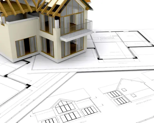 Model domu na planach architektonicznych. Zastanawiasz się, ile trwa budowa domu? To zależy od wielu czynników, ale zaczyna się od projektu.