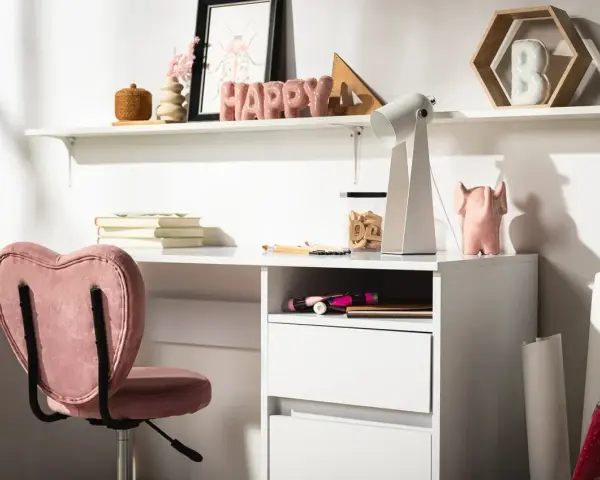 Biurko w kolorze kość słoniowa z różowym fotelem w kształcie serca. Na półce litery tworzące napis "HAPPY".