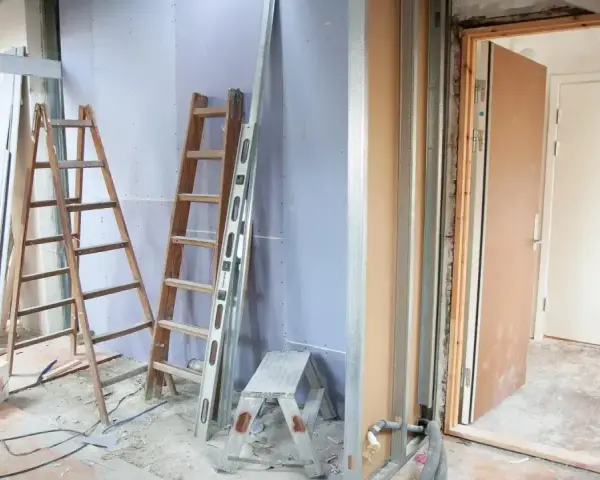 Remont mieszkania 60m2 w toku. Drabiny, poziomica i materiały budowlane wskazują na prace.