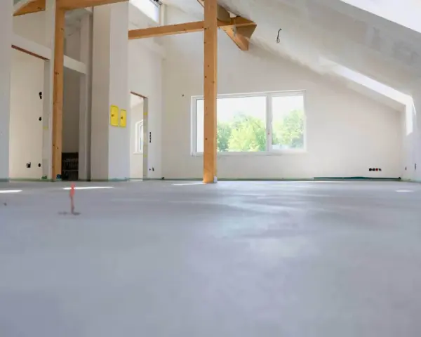 Nowe wnętrze z drewnianymi belkami i oknem, gotowe na posadzkę maszynową. Zastanawiasz się, ile za metr posadzki maszynowej?