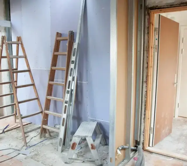 Remont mieszkania 60m2 w toku. Drabiny, poziomica i materiały budowlane wskazują na prace.