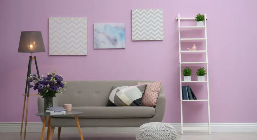 Przytulny salon z szarą kanapą, stolikiem kawowym, lampą i dekoracjami na ścianie w odcieniu **kolor liliowy**.