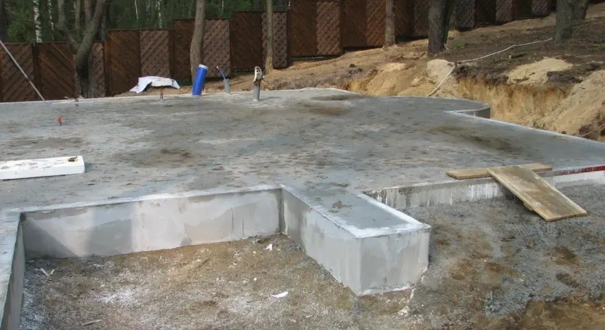Fundament płytowy w trakcie budowy, z widocznymi elementami betonowymi i zbrojeniem.