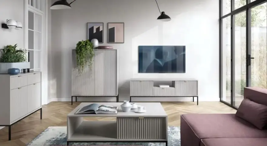 Nowoczesny salon z dużą **ścianą TV**, minimalistycznymi meblami i wygodną, różową sofą.