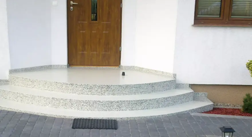 Schody i balkon z żywicy przed drzwiami wejściowymi do domu.