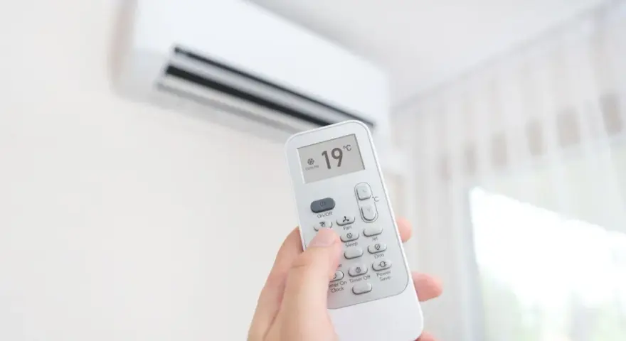 Dłoń trzymająca pilot do klimatyzacji, ustawiona na 19°C. Zastanawiasz się, ile kosztuje montaż klimatyzacji?