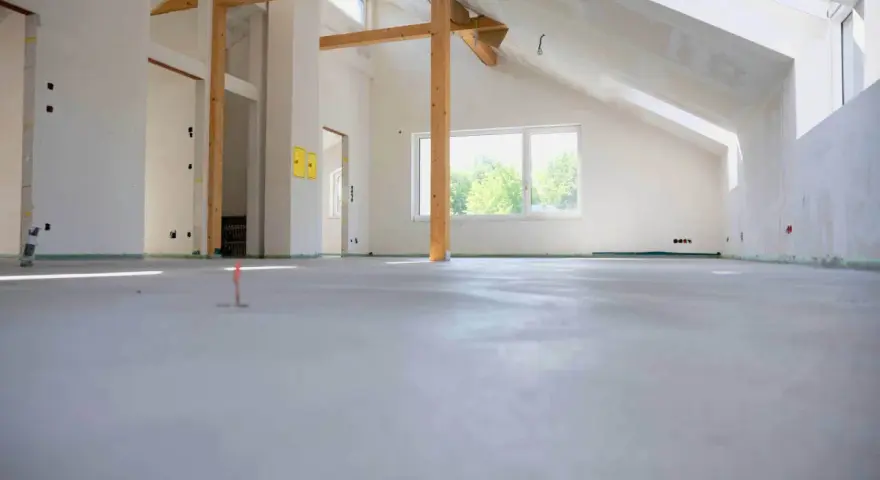 Nowe wnętrze z drewnianymi belkami i oknem, gotowe na posadzkę maszynową. Zastanawiasz się, ile za metr posadzki maszynowej?