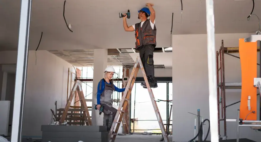 Dwóch budowlańców na drabinach montuje instalację elektryczną. Czy jest ulga na remont mieszkania?