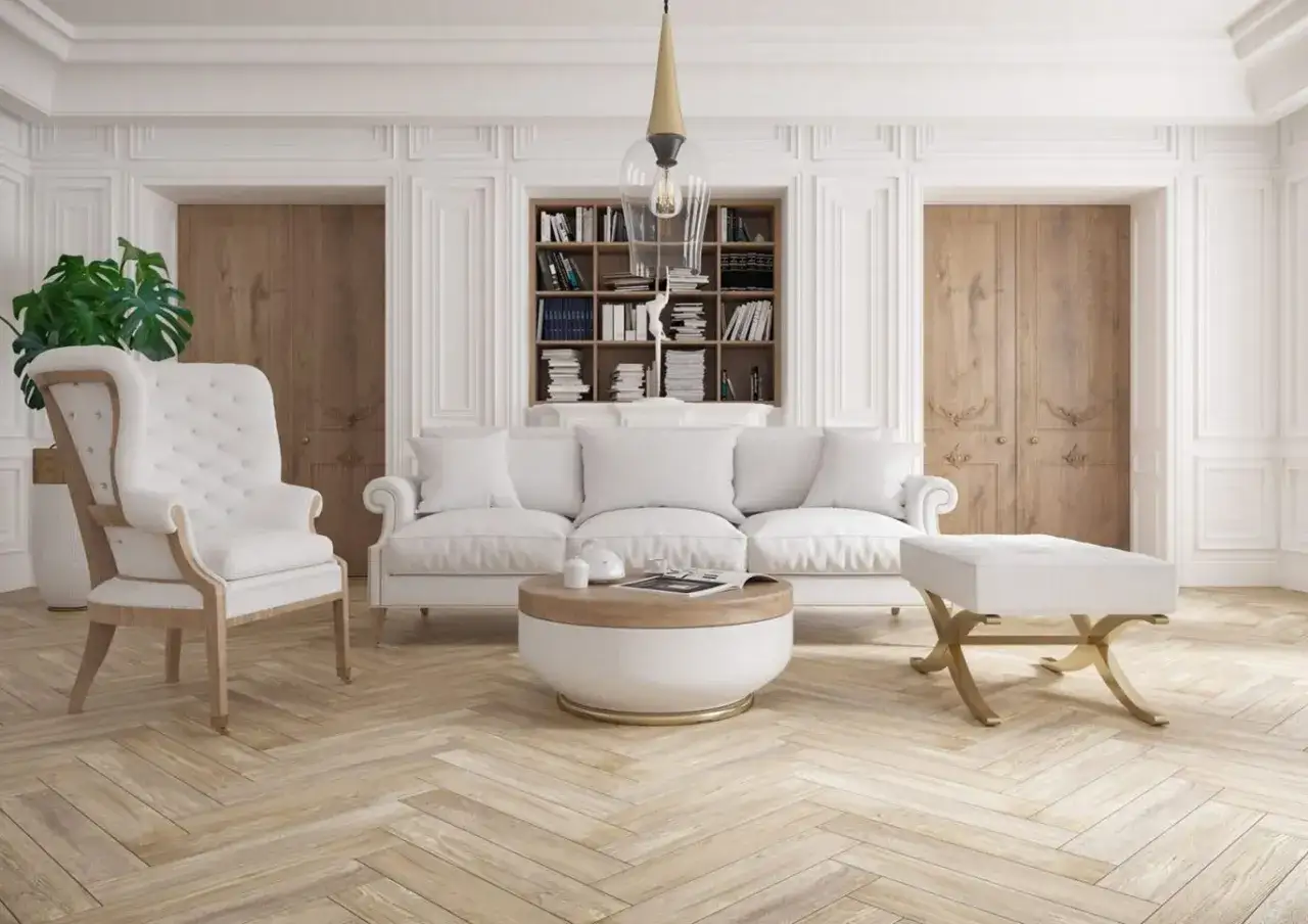 Elegancki salon z białymi meblami, regałem z książkami i ozdobnymi drzwiami. Na suficie widać lampę, a na ścianach subtelne zdobienia, przypominające rozetę.