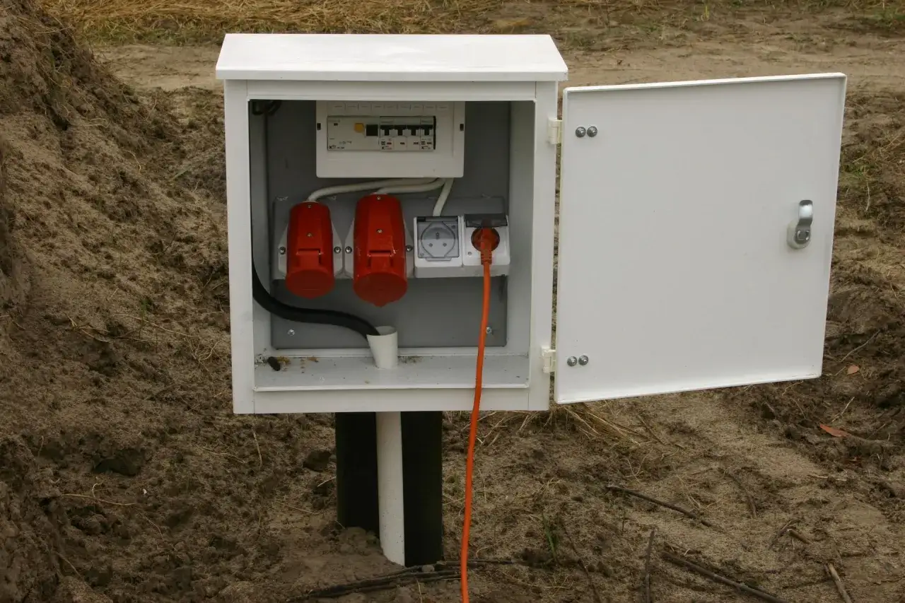 Skrzynka z bezpiecznikami i gniazdami na zewnątrz. Zastanawiasz się, ile kosztuje przyłącze prądu? To może być początek Twojej instalacji.