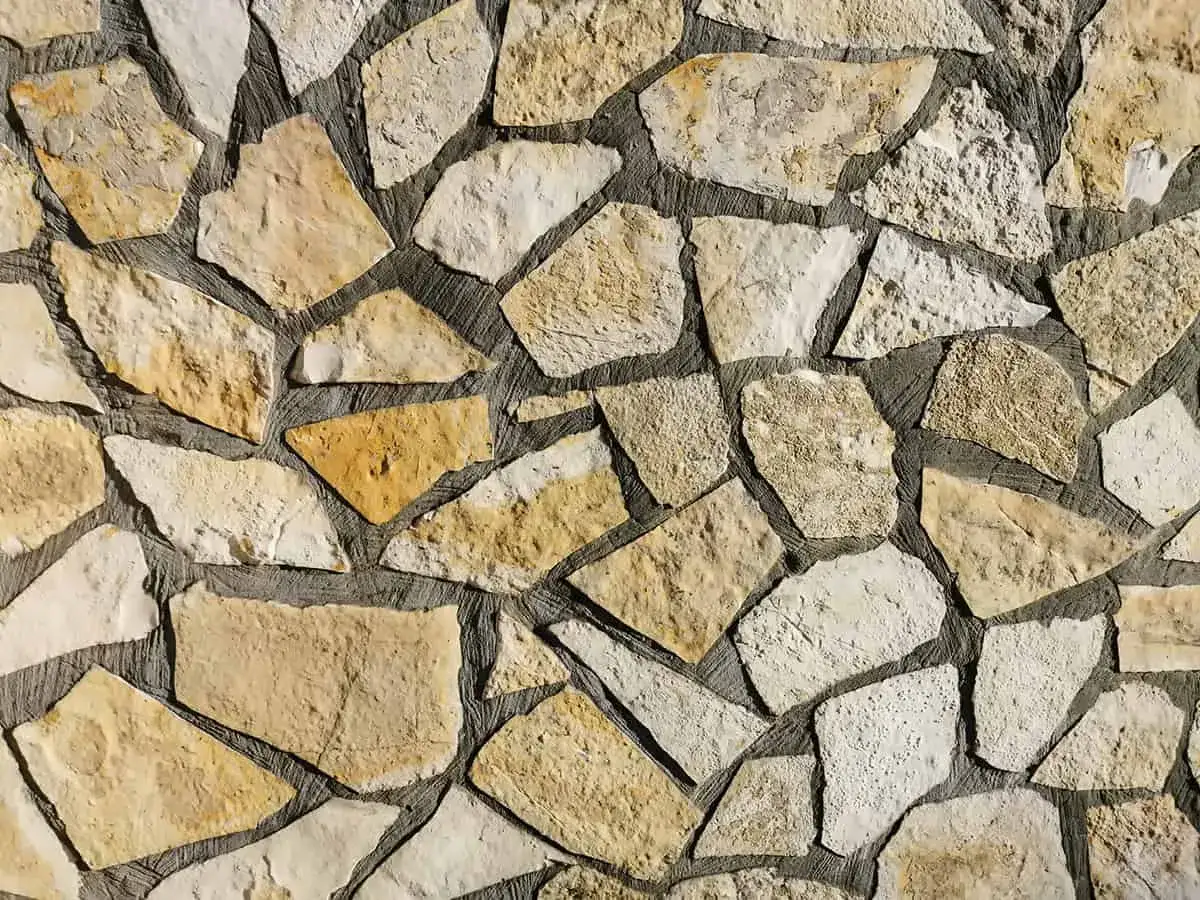 Kamienna ściana z nieregularnych kawałków piaskowca, ułożonych w naturalny wzór.