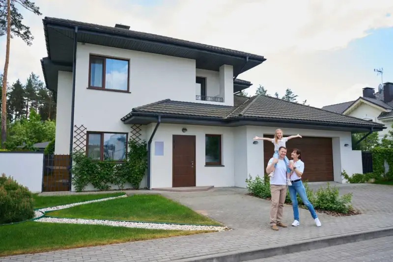 Szczęśliwa rodzina przed nowoczesnym domem. Szacowany koszt budowy domu 220m2.