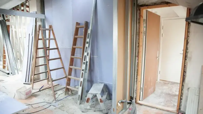 Remont mieszkania 60m2 w toku. Drabiny, poziomica i materiały budowlane wskazują na prace.